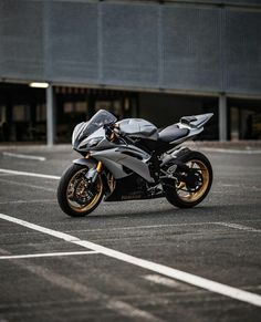 a silver motorcycle parked in a parking lot next to a tall building with two windows