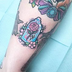 a tattoo on the leg of a person with a rose in a bottle and an owl