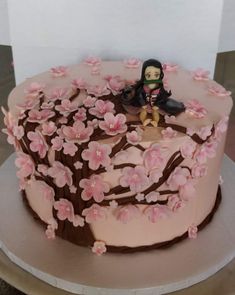 there is a cake decorated with pink flowers and a figure sitting on top of it