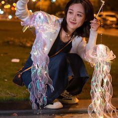 a woman kneeling on the ground with some lights in front of her and holding something up