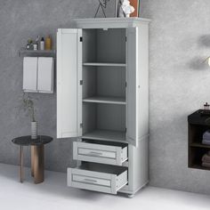 a white cabinet with drawers and shelves in the corner next to a wall mounted towel dispenser