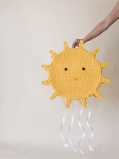 a person holding a paper plate with a yellow sun on it's face and hands