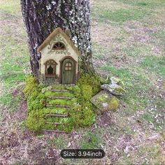 a small house made out of moss on the ground next to a tree with steps leading up to it