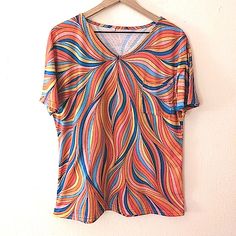 65% Cotton 35% Polyester Fitted Tee Front Chest Pocket Retro Looking Swirly Stripes Bright And Bold Flat Lay Measurements: Bust- 20" Length- 26" Retro Orange V-neck Top, Blue V-neck Top With Colorful Pattern, Orange Vibrant Print Short Sleeve Tops, Spring Orange Tops With Colorful Pattern, Retro Blue Top With Colorful Pattern, Boxy Crop Top, Red Long Sleeve Shirt, Lacoste Women, White Tee Shirts