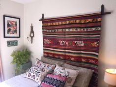 a bed with pillows and blankets on top of it next to a wall mounted clock