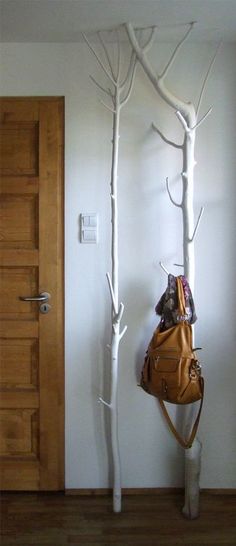 two white trees with purses hanging from them in front of a door and a wooden floor