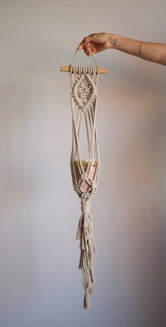 a hand holding a macrame hanging from a wall