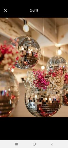 several disco balls hanging from the ceiling with flowers in them