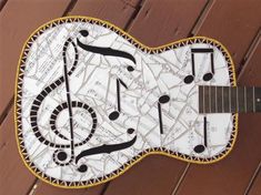 an electric guitar made out of sheet music notes and musical notations is displayed on a wooden deck