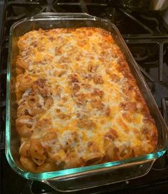 a casserole dish sitting on top of an oven with cheese and meat in it