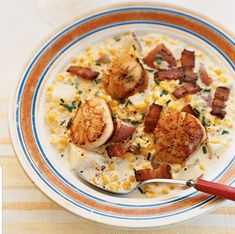 a white plate topped with scallops and corn on top of a table next to a fork