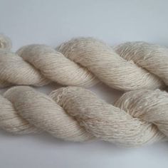 two skeins of white yarn sitting on top of each other in front of a white background