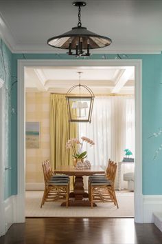 an open door leading to a dining room with blue walls and wood floors, along with a chandelier hanging from the ceiling