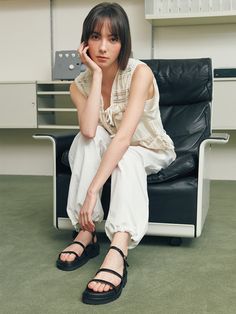 a woman sitting on top of a black chair next to a white desk and book shelf