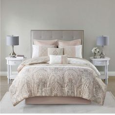 a bed with white and pink comforter in a bedroom next to two nightstands