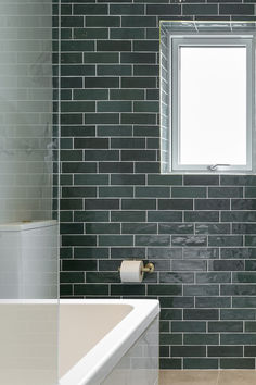 a white bath tub sitting next to a window in a bathroom