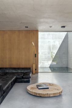 a living room with a black leather couch and wooden table in front of the wall