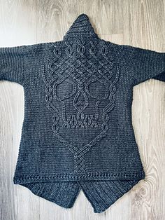 a knitted sweater with an intricate design on the front and back, sitting on a wooden floor