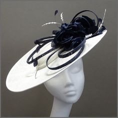 Stunning pure white split brim sinamay disc fascinator / hatinator. The split at the back gives added interest making this design truly unique. Decorated throughout with navy, silk effect, flower clusters, loops of navy sinamay and a mix of delicately cut feathers. Perfect for weddings and derby/race days. Made on a headband. This design is available in other colours on request. All of our designs can be made to order in a range of different colours or styles, see our colour chart: https://jacqu White Fitted Boater Hat With Flat Brim, White Adjustable Top Hat For Races, White Fitted Boater Hat With Short Brim, White Brimmed Top Hat For Royal Ascot, White Brimmed Fascinator For Church, White Brimmed Mini Hat For Evening, White Sinamay Mini Hats For Spring, White Fitted Top Hat With Flat Brim, Spring White Mini Hats In Sinamay