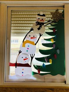 a window decorated with paper snowmen and christmas trees