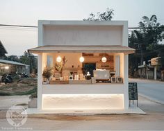 a small white building sitting on the side of a road next to a street light