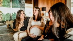 three women laughing while sitting on a couch