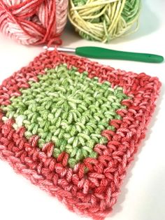 a crocheted square with two balls of yarn next to it