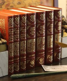 a row of red books sitting on top of a wooden table