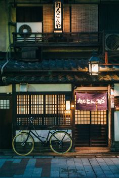 a bicycle is parked in front of a building with lanterns on it's roof