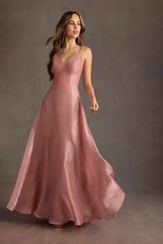 a woman in a long pink dress is posing for the camera with her hand on her hip