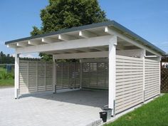 a white and gray shed sitting on top of a lush green field