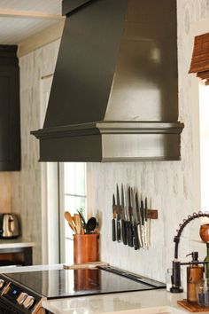 a kitchen with an oven, stove and utensils on the wall above it