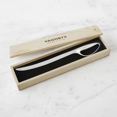 a wooden box with a knife in it on a marble countertop next to a black and white object