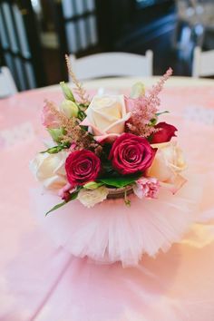 a bouquet of roses is sitting on a pink tablecloth with white and red flowers