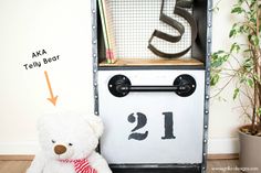 a white teddy bear sitting next to a book shelf with letters and numbers on it