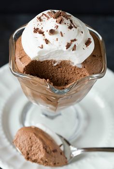 an ice cream sundae with chocolate shavings and whipped cream on top is served in a glass dish