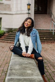 a woman is sitting on a concrete bench smiling and looking at the camera with her legs crossed