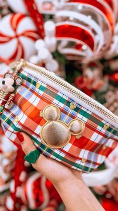 a hand holding up a small purse in front of candy canes and christmas decorations