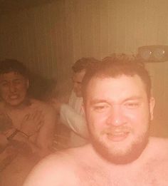 three men are sitting in a bathtub and one man is smiling at the camera