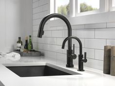 a kitchen sink with black faucet and soap dispenser next to it