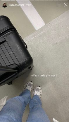 a man standing next to a black piece of luggage on top of a cement floor