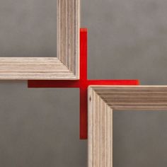 four square pieces of wood with red tape sticking out of them