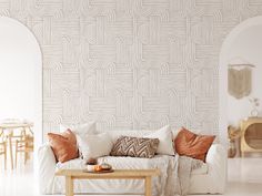 a living room with white furniture and orange pillows on the couch, in front of an archway