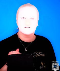 a person with a white mask on holding a black case in front of their face