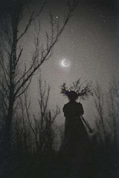 a person standing in the woods at night with a full moon behind them and trees