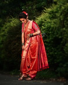 a woman in an orange and red sari standing on the side of a road