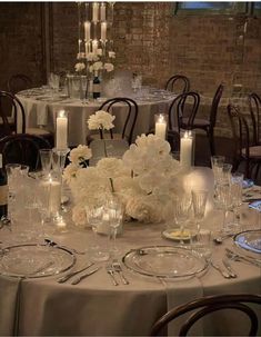 the table is set with white flowers, candles and wine glasses for an elegant centerpiece