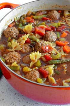 a red pot filled with pasta and meatballs