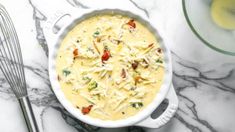 a casserole dish with cheese and vegetables in it on a marble counter top