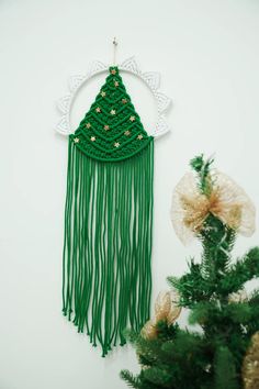 a green christmas tree decoration hanging on the wall next to a pine tree with gold stars